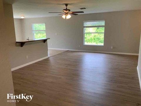 A spacious room with wooden flooring and a ceiling fan.
