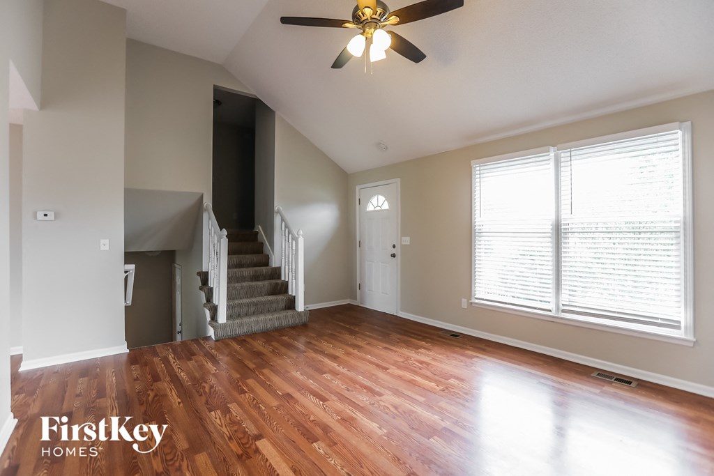 an empty living room with wood floors and a ceiling fan