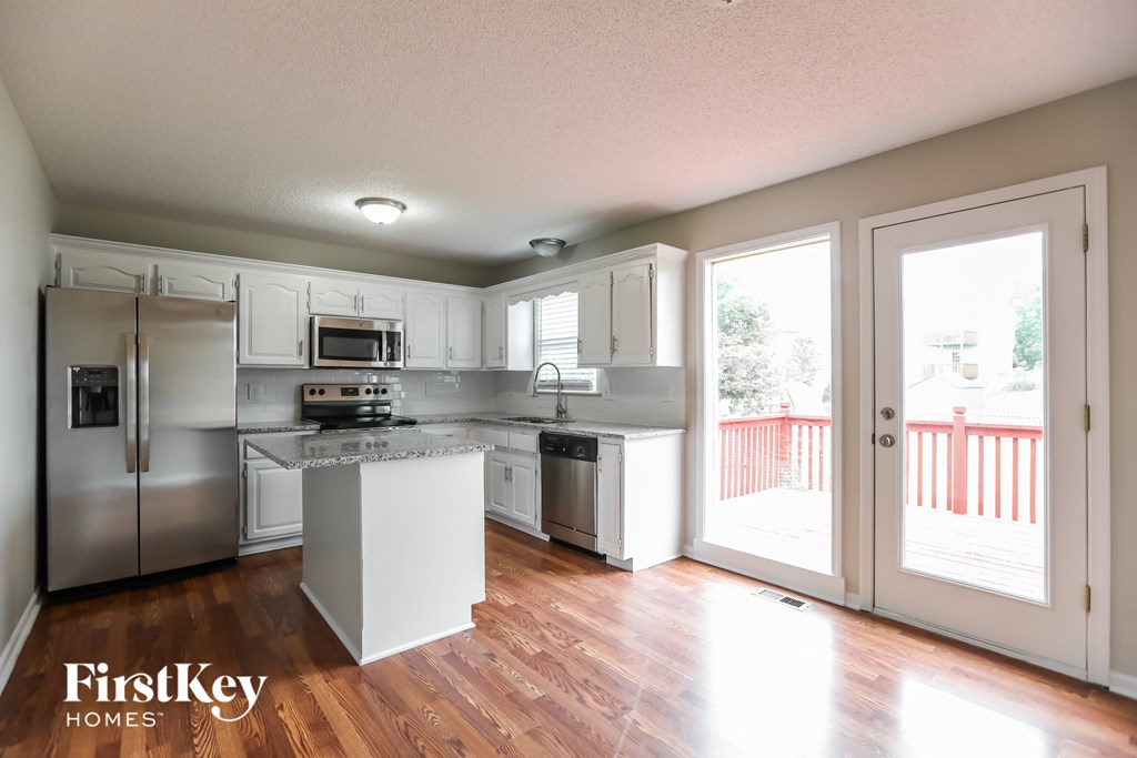 a kitchen with white cabinets and stainless steel appliances and sliding glass doors