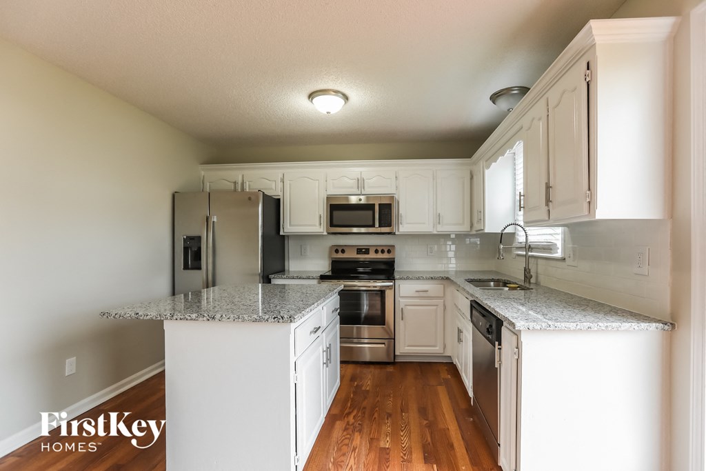 a kitchen with white cabinets and granite counter tops