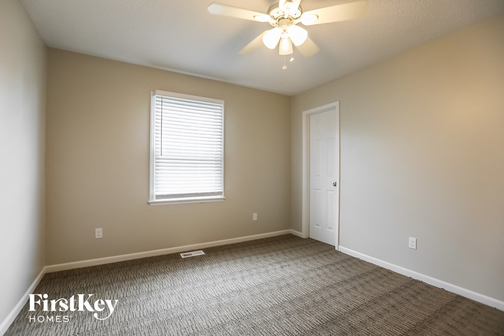 an empty room with a ceiling fan and a window