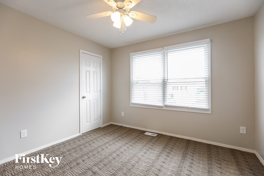an empty living room with a ceiling fan and a window