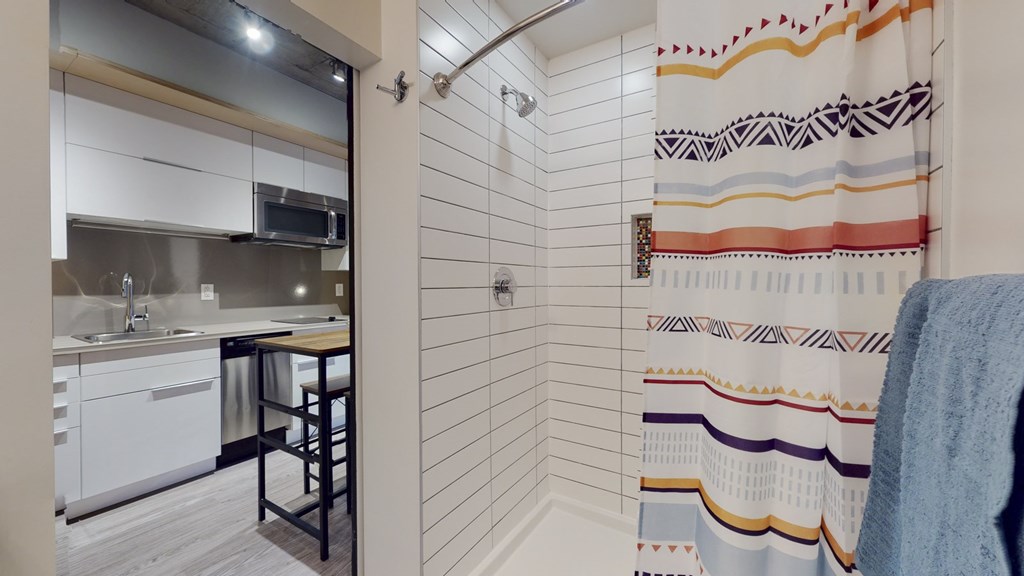 a bathroom with a shower and a sink and a kitchen