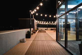 a roof terrace at night with string lights and wooden decking