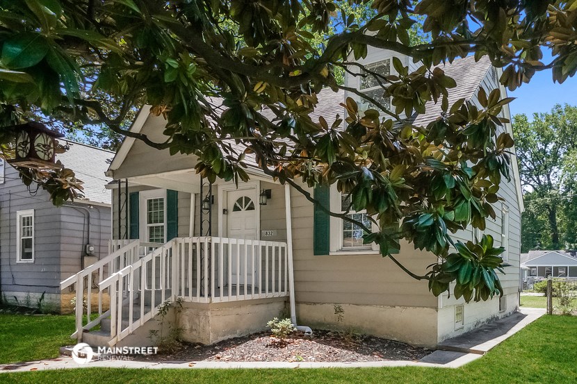 a white house with a porch and a tree in front of it