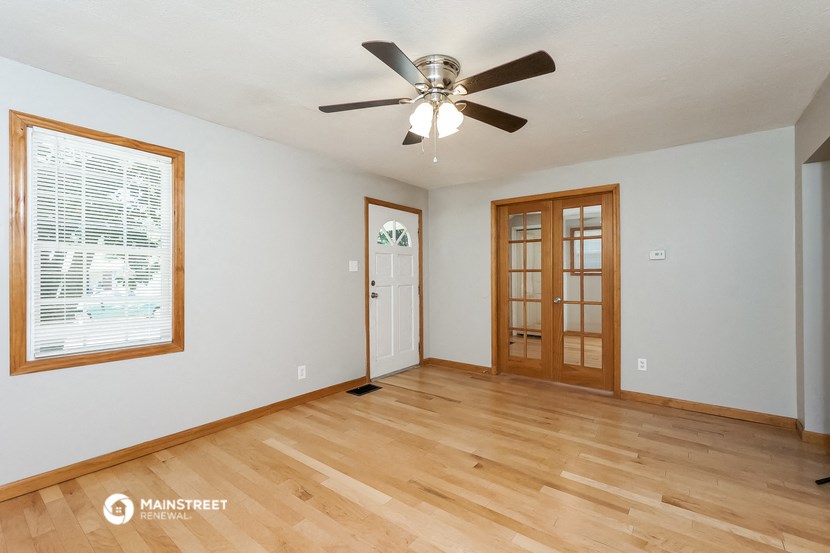 an empty living room with wood floors and a ceiling fan