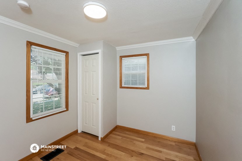 the living room of a house with a wooden floor and a white door and window