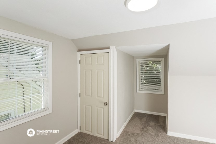 a bedroom with a door to a closet and a window