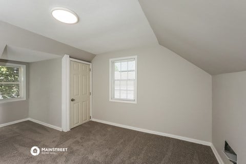 the living room of an attic with carpet and a white door