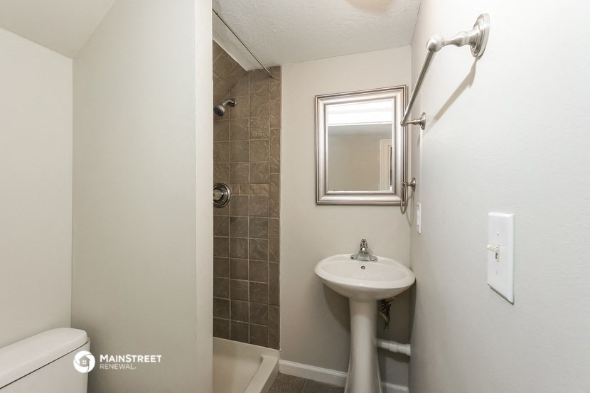 a small bathroom with a sink and shower and a mirror