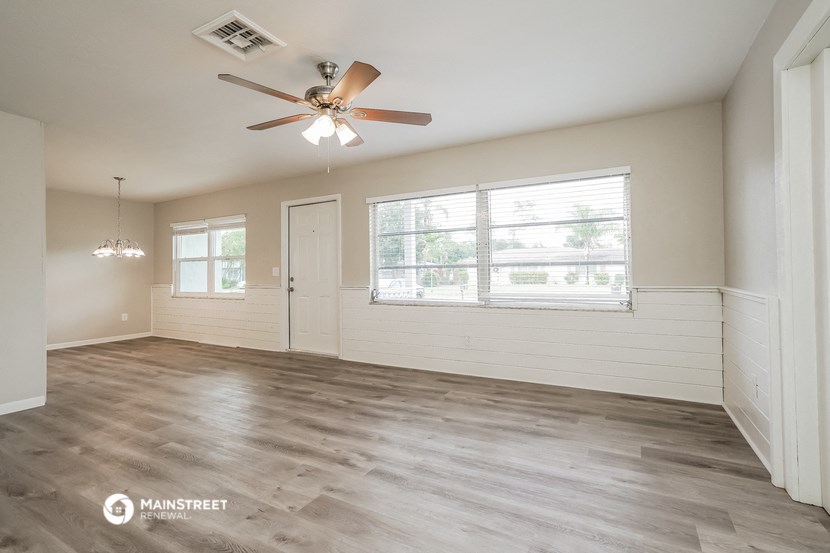 an empty living room with a ceiling fan and a window