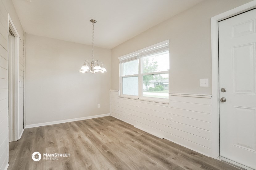 a bedroom with white walls and wood flooring and a window