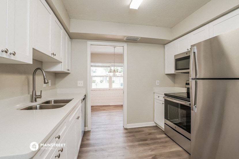 an empty kitchen with white cabinets and stainless steel appliances