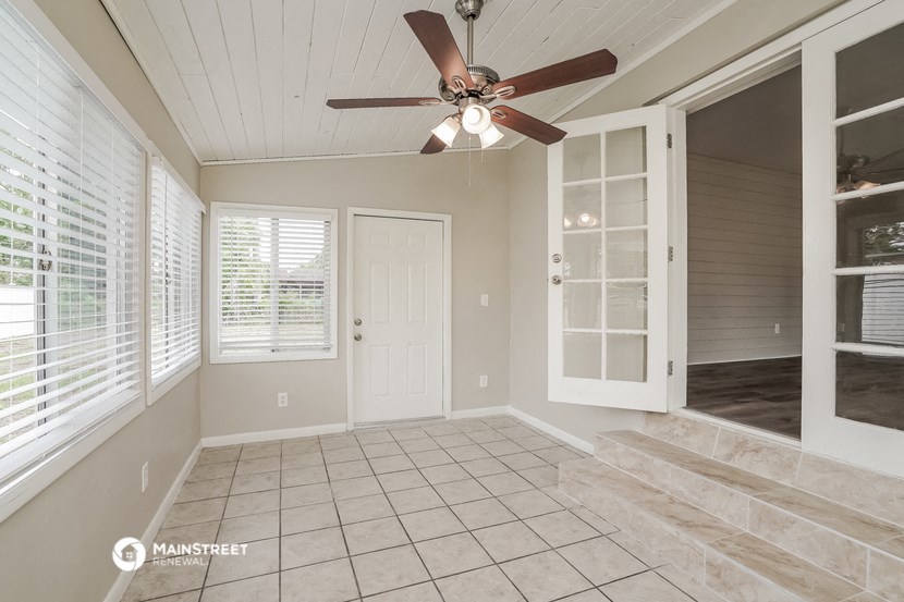 a sun room with a ceiling fan and a staircase