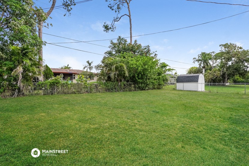 a backyard with a fence and a shed and a grass field