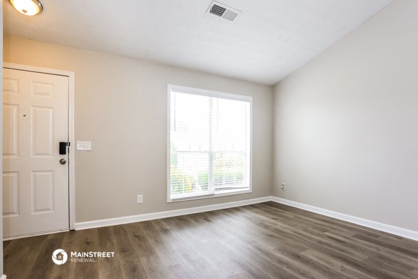 the spacious living room with a large window and wood flooring