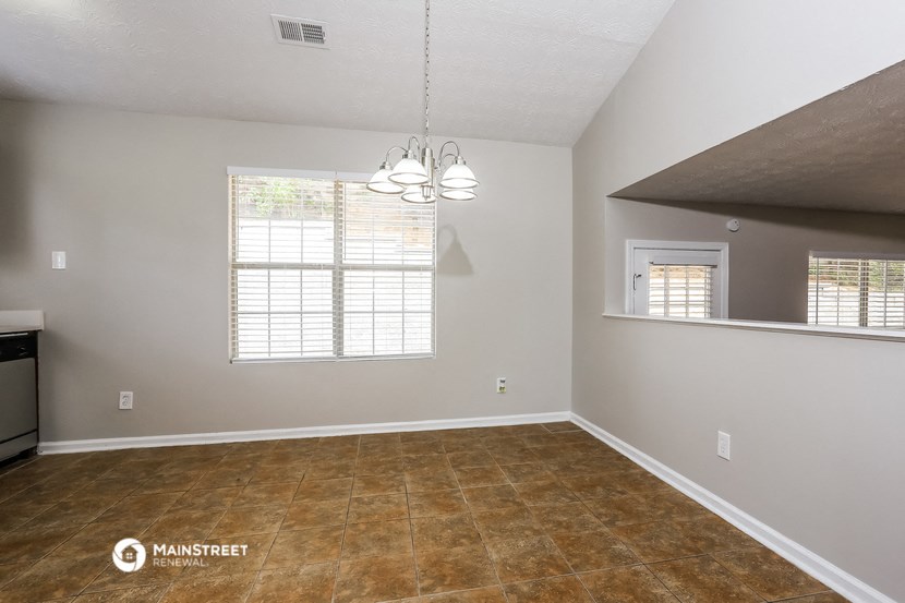 an empty living room with a window and a kitchen