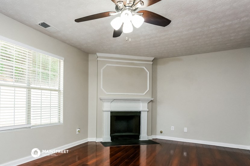 the living room of a house with a fireplace and a ceiling fan