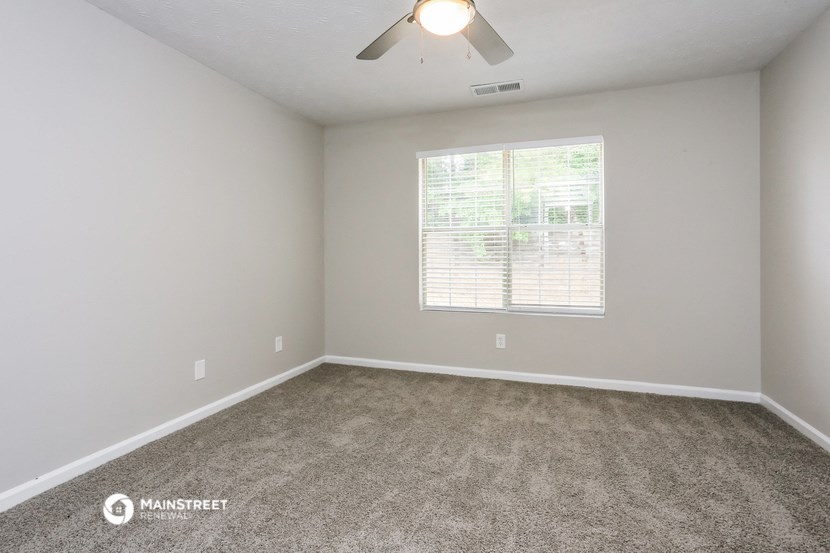the spacious living room with carpeting and a large window