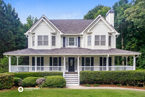 a white house with a wraparound porch and a lawn