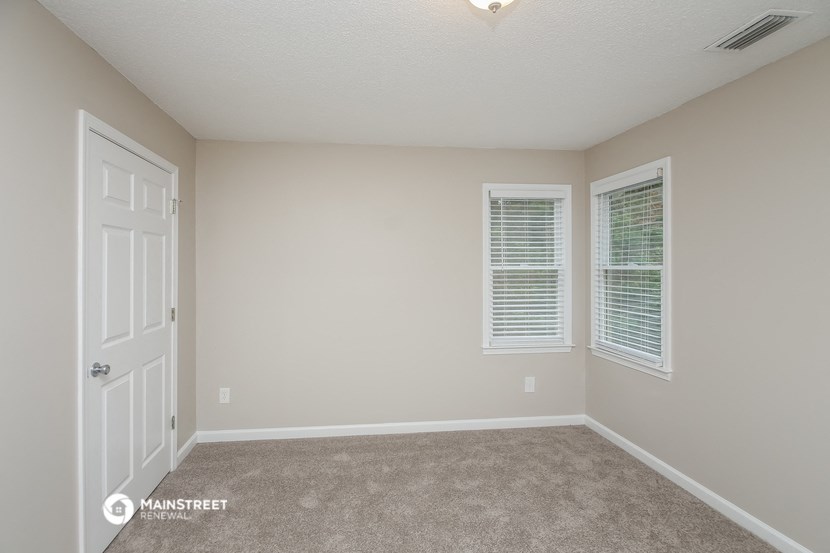 an empty room with two windows and a white door
