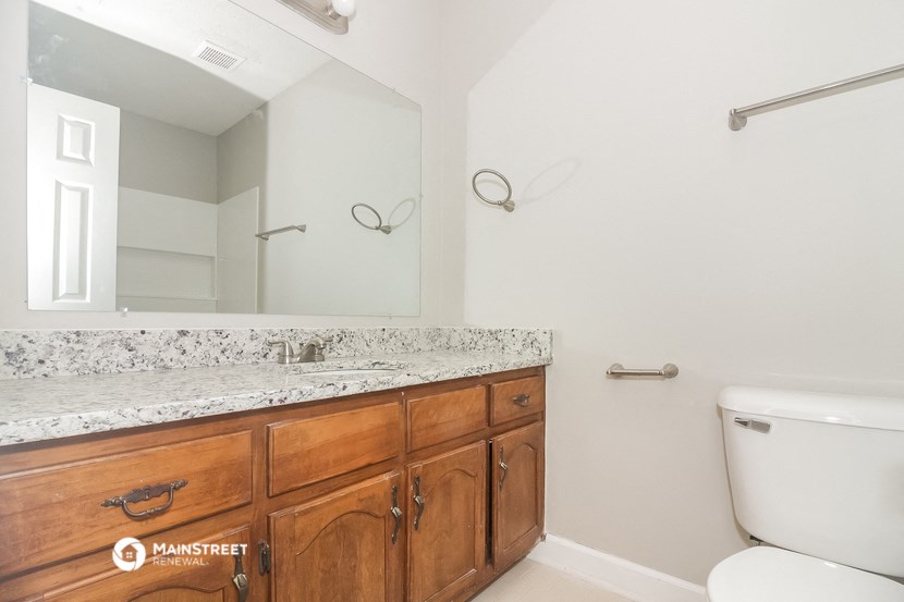 a bathroom with wooden cabinets and a large mirror and a toilet
