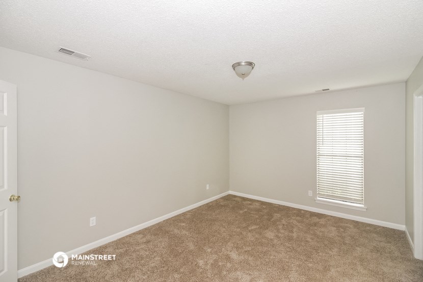 the spacious living room with carpeting and a window