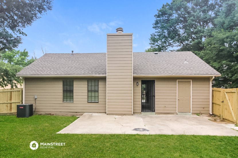 a tan brick house with a driveway and a wood fence