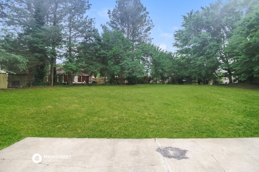 a large yard with trees and a house in the background