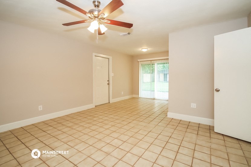 an empty living room with a ceiling fan and a tiled floor