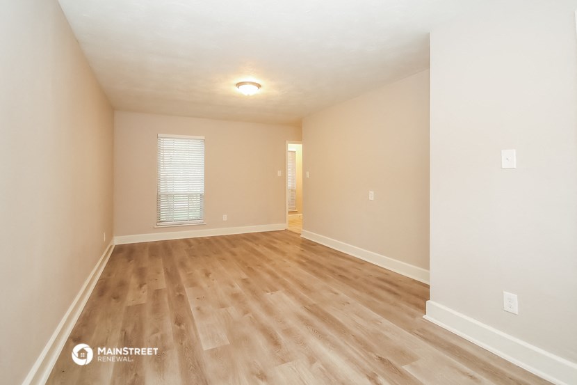 the spacious living room with hardwood flooring and white walls