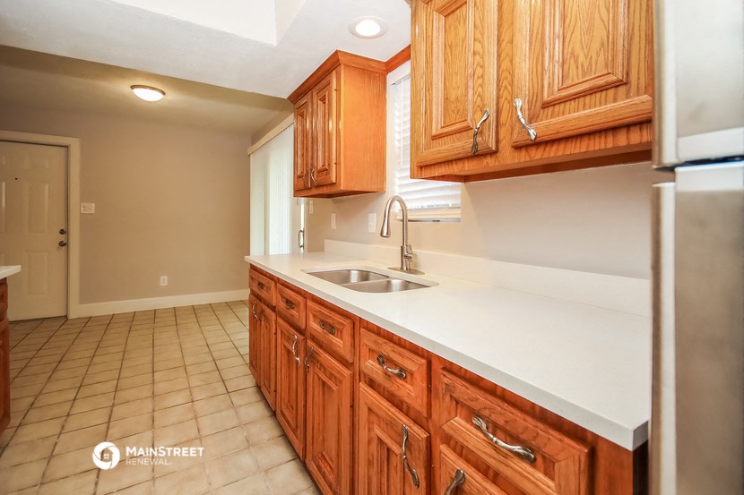 a kitchen with wooden cabinets and white countertops and a sink