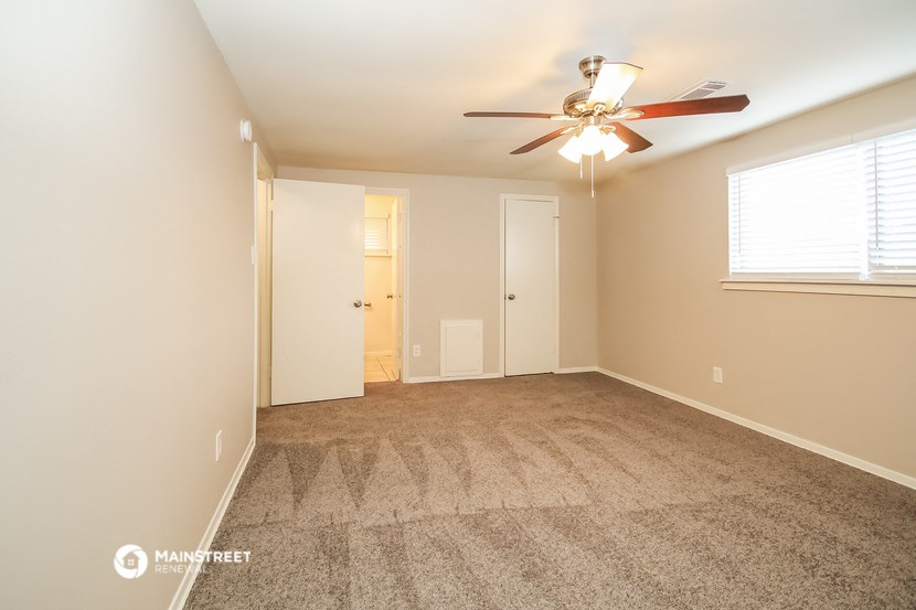 an empty living room with carpet and a ceiling fan