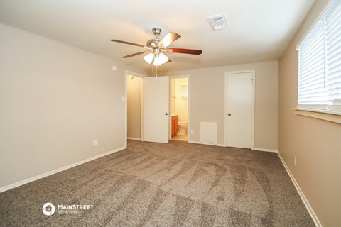 the spacious living room with carpet and a ceiling fan
