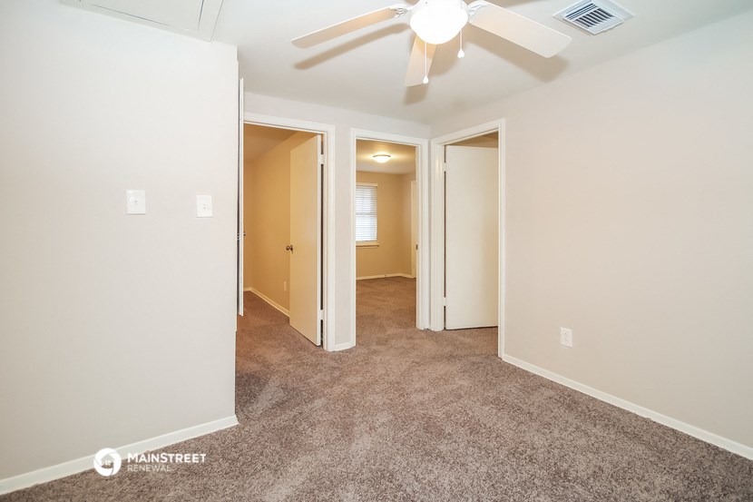 a living room with carpet and a ceiling fan