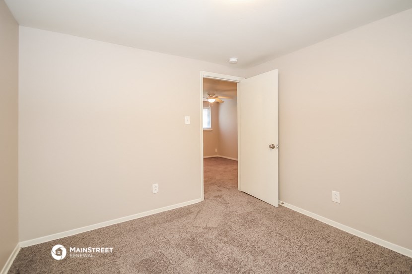 a bedroom with carpet and a door to a hallway