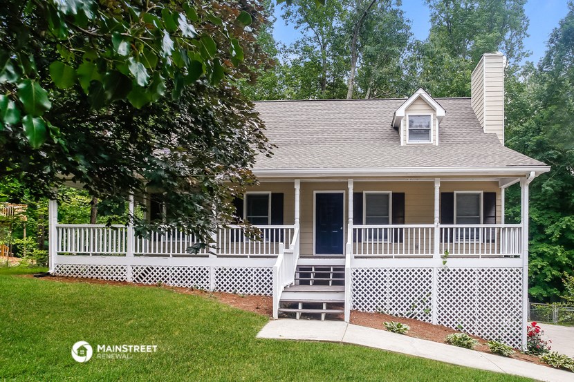 a white house with a porch with a white fence