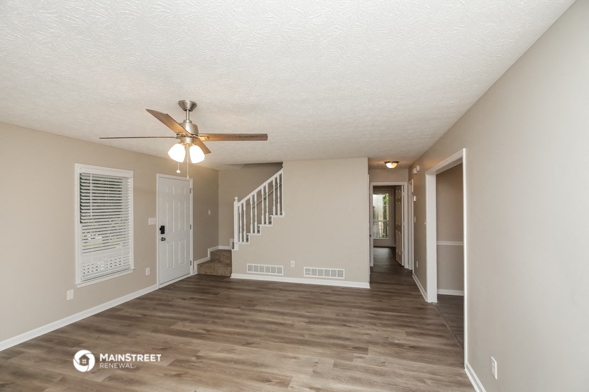 the living room and hallway of a renovated house with a ceiling fan