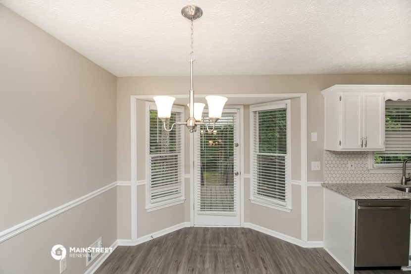 the kitchen and dining room of a manufactured home with windows and a chandelier