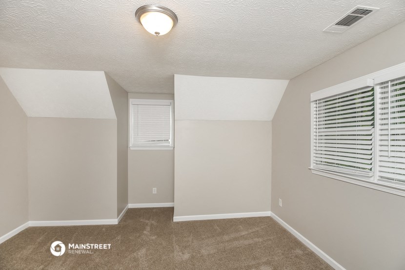 the spacious living room of a manufactured home with a carpeted floor and a window