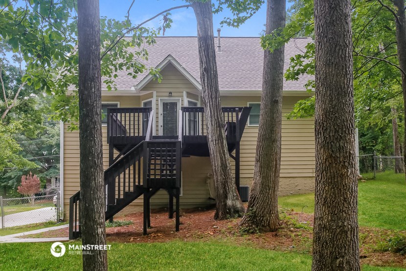 a house with a deck in the middle of three trees
