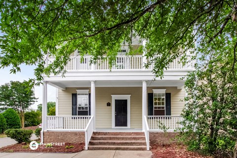 a white house with a white porch and a tree