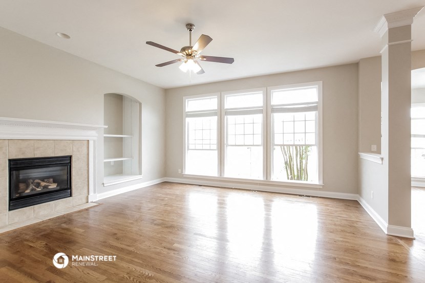 an empty living room with a fireplace and a ceiling fan