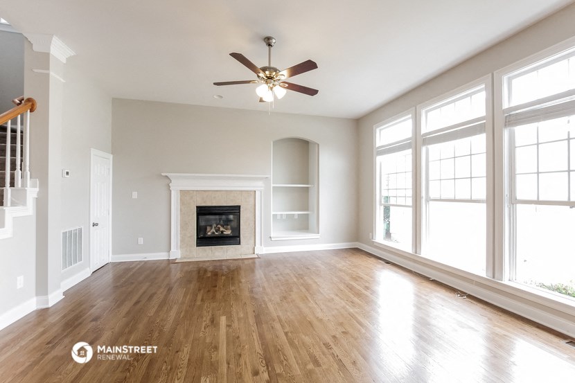 an empty living room with a fireplace and a ceiling fan