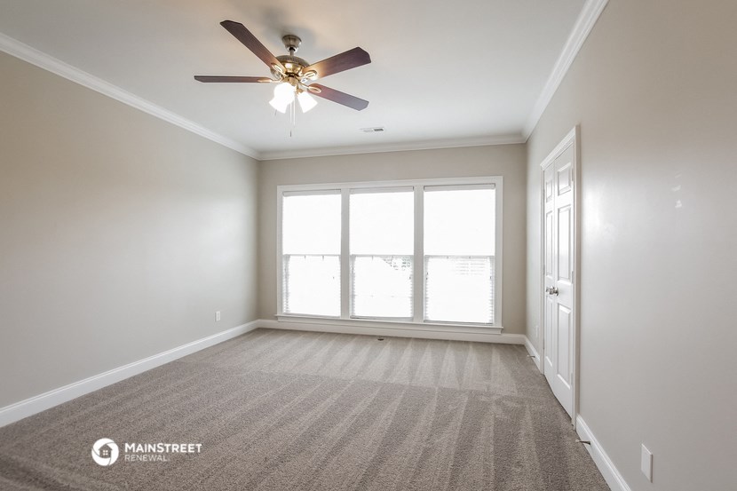 an empty living room with a ceiling fan and a window