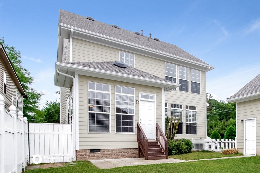 the front of a white house with a white fence