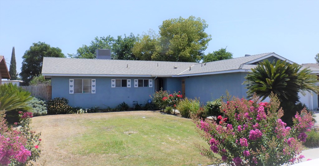 a blue house with a yard and flowers