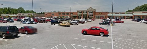 a parking lot filled with cars in front of a shopping center