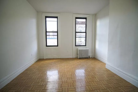 A room with a wooden floor and two windows.