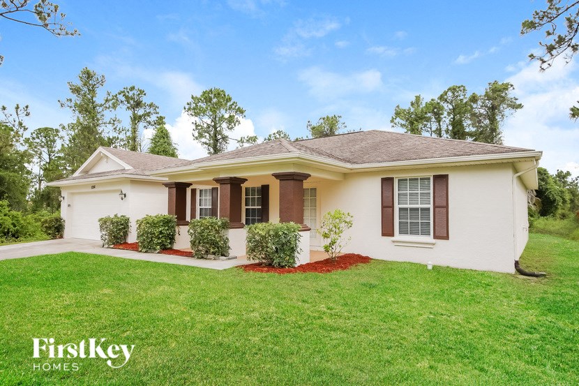 a small white house with a lawn and some bushes
